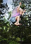 Girl wearing wings and jumping in forest