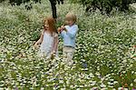 Children walking in field of flowers