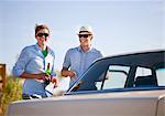 Men drinking beer and smoking by car