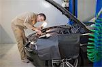 Mechanic working on car engine in garage