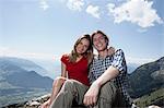 Smiling couple sitting on hilltop