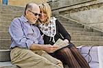 Older couple reading city map on steps