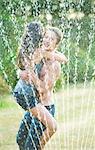 Friends hugging in sprinkler