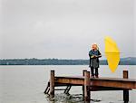 Girl holding yellow umbrella on dock