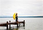 Children with yellow umbrella on dock