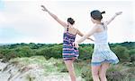 Women playing airplane on beach