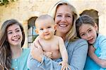 Mother and daughters hugging outdoors