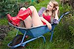 Woman sitting in wheelbarrow in garden