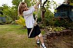 Girl playing on rope swing in backyard