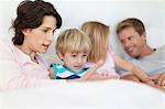 Family relaxing in bed together