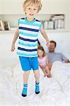 Boy jumping on parents' bed