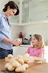 Mother helping daughter peel potatoes