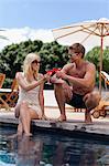 Couple toasting each other by pool