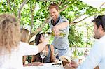 Man pouring wine for friends at table