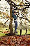 Boy playing on tree outdoors