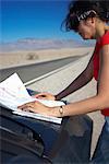 Woman reading map on rural road