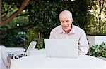 Older man using laptop outdoors