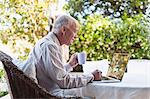 Older man using laptop outdoors