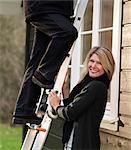 Smiling woman holding ladder for husband