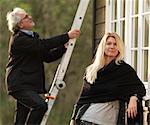 Woman smiling as husband climbs ladder