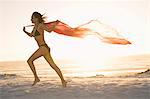 Woman running with sarong on beach