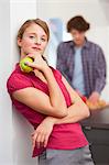 Woman eating apple in kitchen