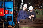 Workers examining metal in steel forge