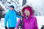 Couple carrying skis and poles in snow