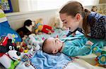 Girl playing with baby brother on bed