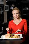 Woman eating plate of food in cafe