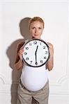 Pregnant woman holding clock