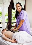 Woman having hot stone massage in spa