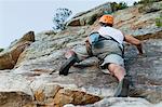 Climber scaling steep rock face