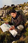 Hiker reading map in rocky field