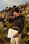 Hiker using binoculars in rocky field