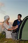 Couple setting up tent on hillside