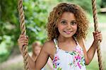 Smiling girl standing on tree swing