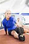 Woman stretching on indoor track in gym