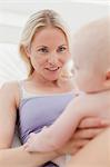 Mother playing with baby on bed