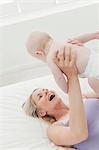 Mother playing with baby on bed