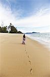 Woman making footprints on sandy beach
