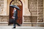 Businessman carrying umbrella on street