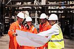 Workers with blueprints at oil refinery