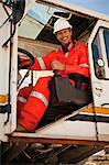 Worker operating crane at oil refinery