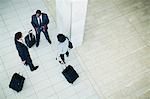 Business people rolling luggage in lobby