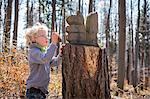 Boy examining pine cone in forest