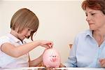 Daughter putting money in piggy bank