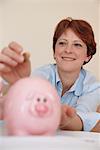 Woman putting money in piggy bank