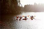 Kayakers holding oars on still lake