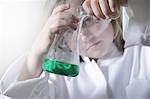 Girl pouring liquid into beakers